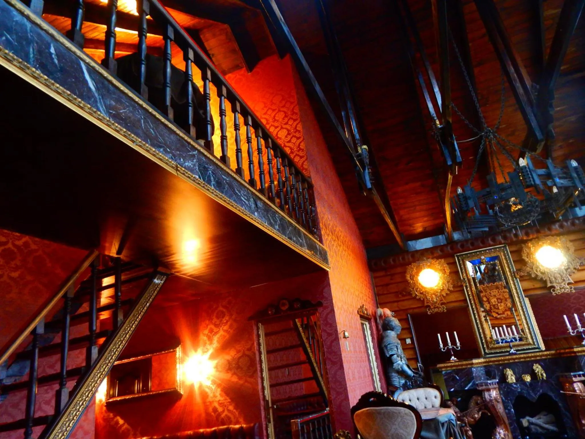 Un escalier en colimaçon mène à une mezzanine dans un espace intérieur décoré de bois et de luminaires.