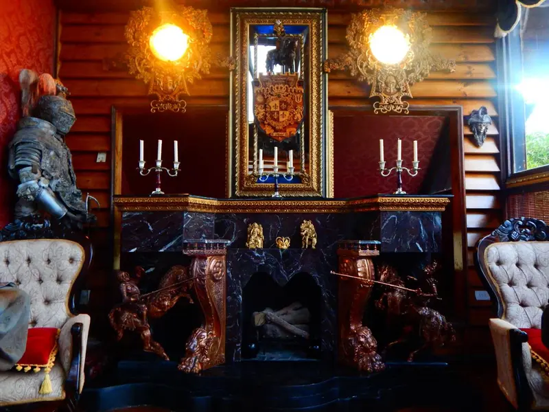 Une cheminée en pierre sombre orne un intérieur chaleureux avec des fauteuils et des lustres.