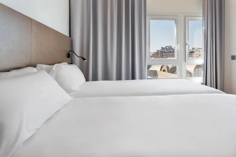 Une chambre lumineuse avec un grand lit recouvert de draps blancs.