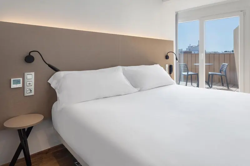Une chambre lumineuse avec un grand lit et un balcon.