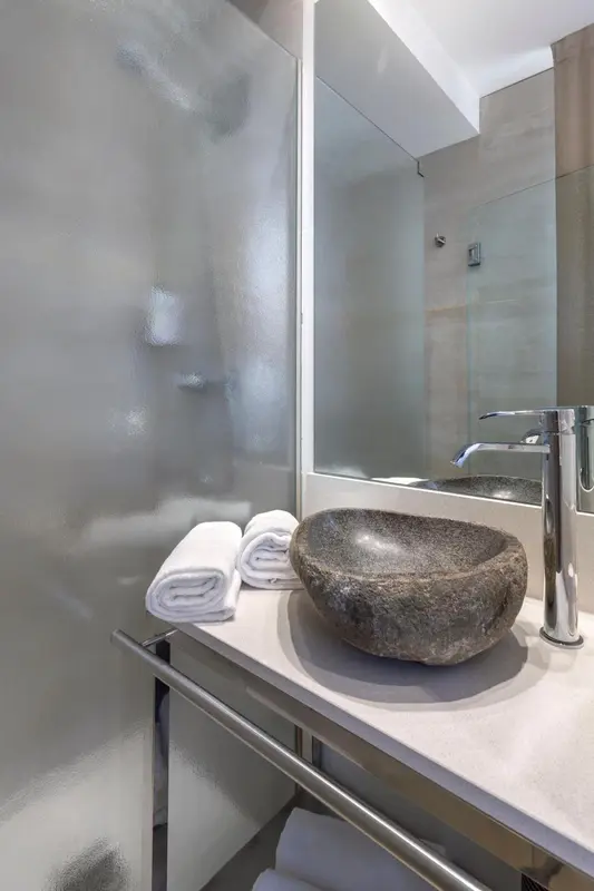 Un lavabo moderne et des serviettes pliées sur un meuble clair dans une salle de bain.