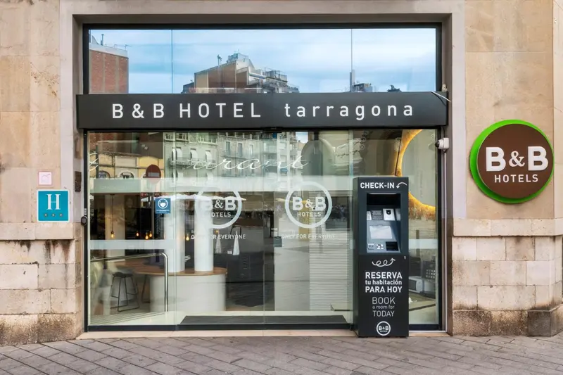 Façade d'un hôtel avec une entrée vitrée et un panneau d'information.