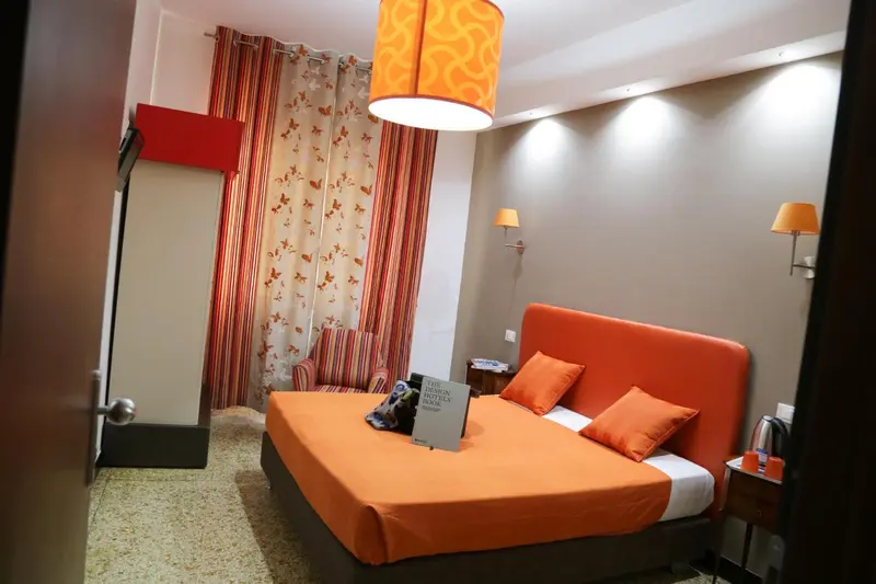 Une chambre à coucher avec un grand lit recouvert d'une couette orange et de coussins assortis.