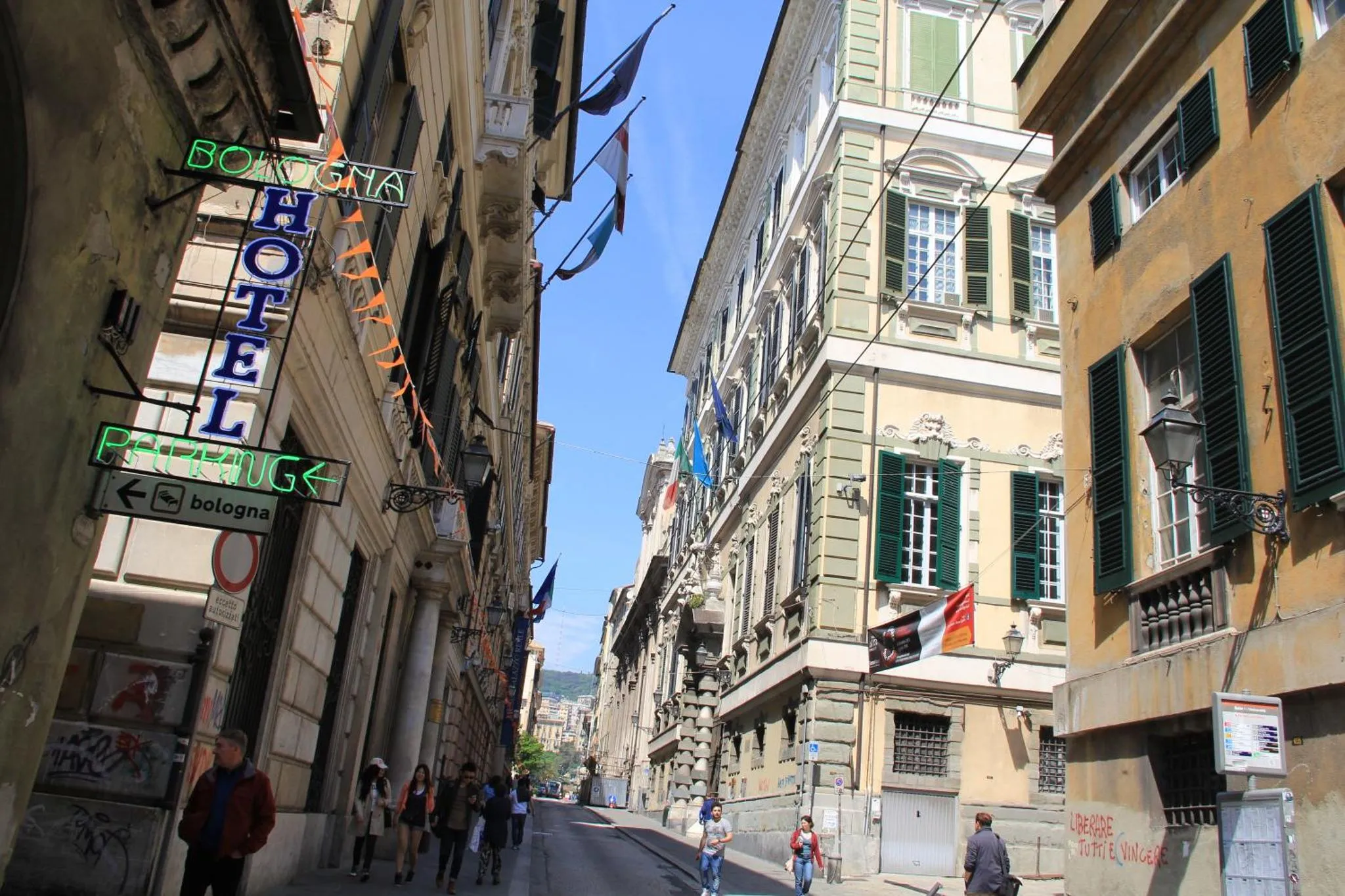 Rue étroite en ville avec des bâtiments anciens et des passants.