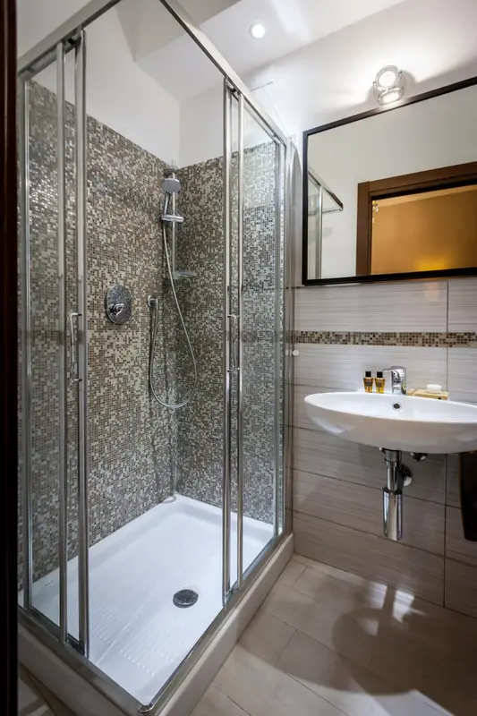 Une douche à l'italienne moderne avec des mosaïques grises et un grand miroir.