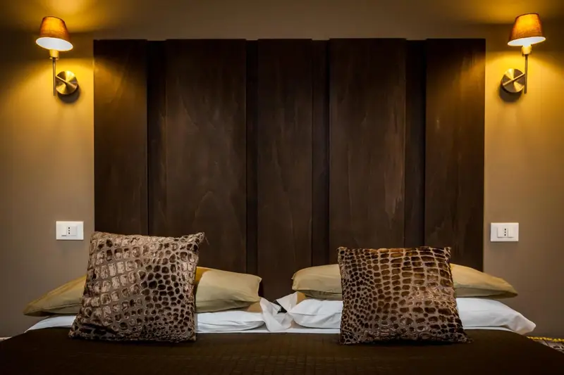 Un lit double avec des oreillers et une tête de lit en bois sombre.