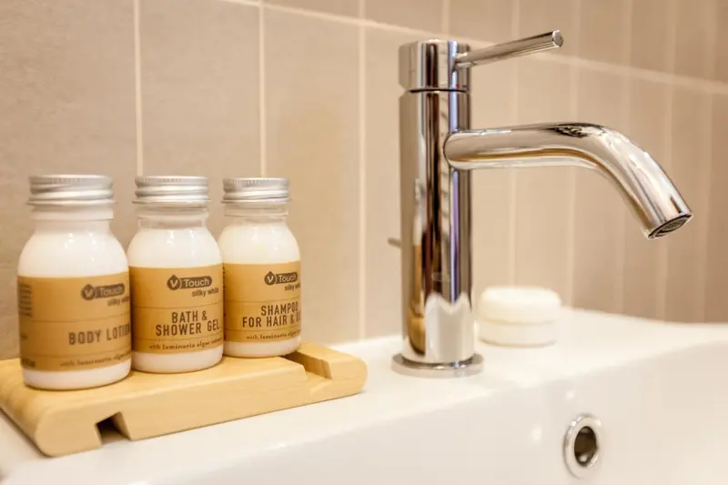 Un lavabo blanc avec des produits de toilette sur un plateau en bois.