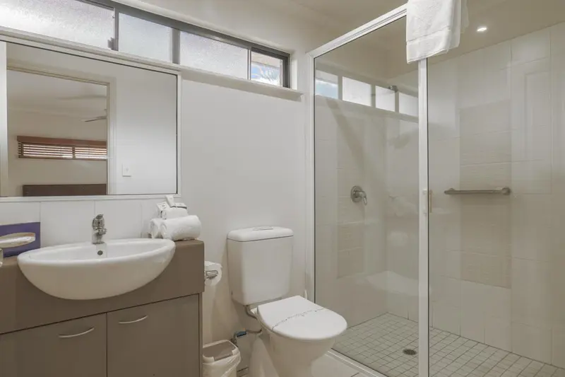 Une salle de bain claire avec douche vitrée et lavabo.
