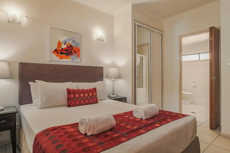 Une chambre lumineuse avec un grand lit et un accès à une salle de bain.