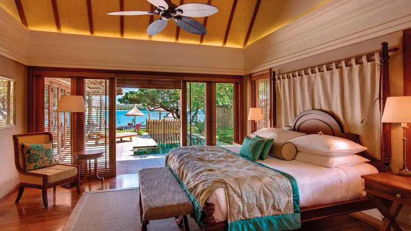 Une chambre lumineuse avec un lit king-size donnant sur une terrasse et une piscine.