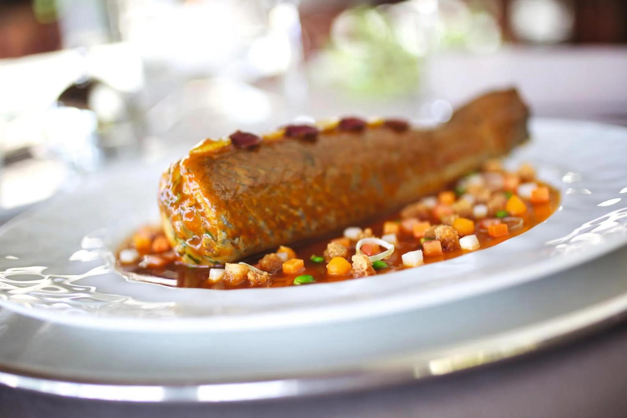 Un plat de poisson élaboré est présenté sur une assiette blanche.