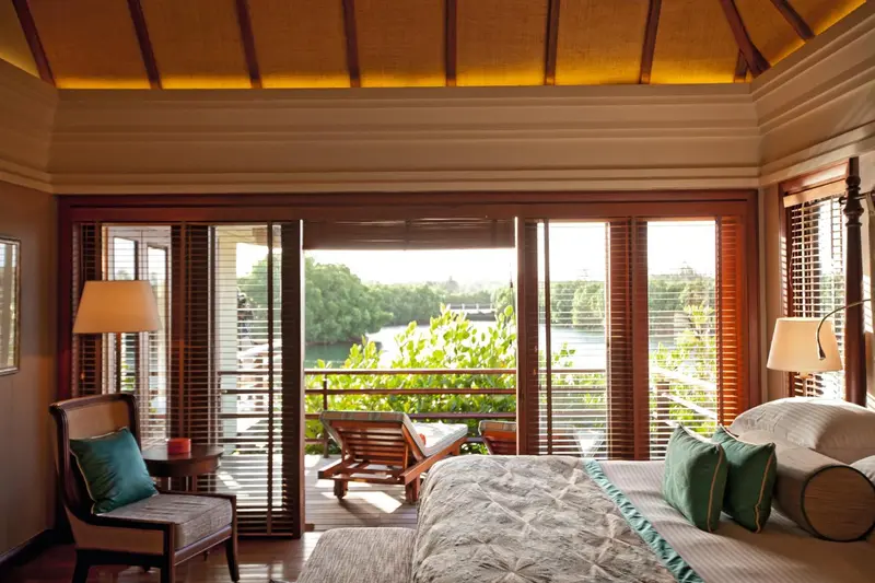 Une chambre lumineuse s'ouvre sur une terrasse avec vue sur la végétation.