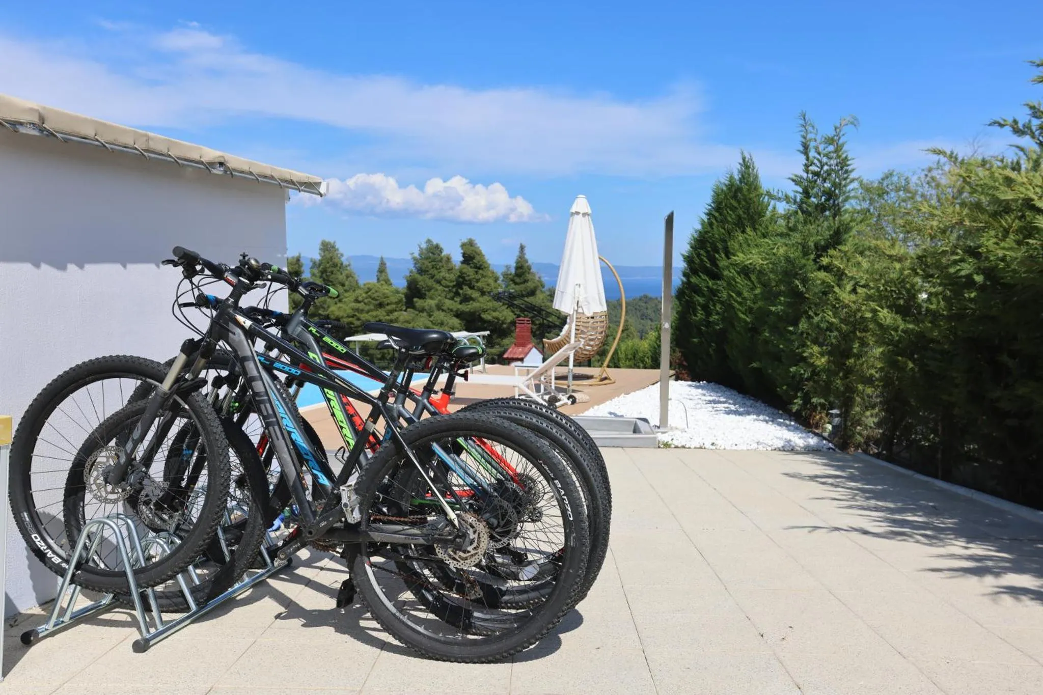 Des vélos sont rangés sur une terrasse ensoleillée avec vue sur la mer.
