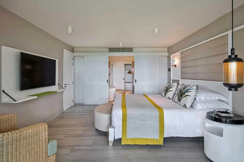Une chambre lumineuse avec un grand lit et un téléviseur mural.