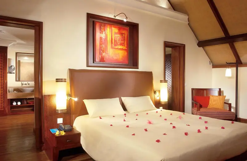 Une chambre lumineuse avec un grand lit décoré de pétales de fleurs.