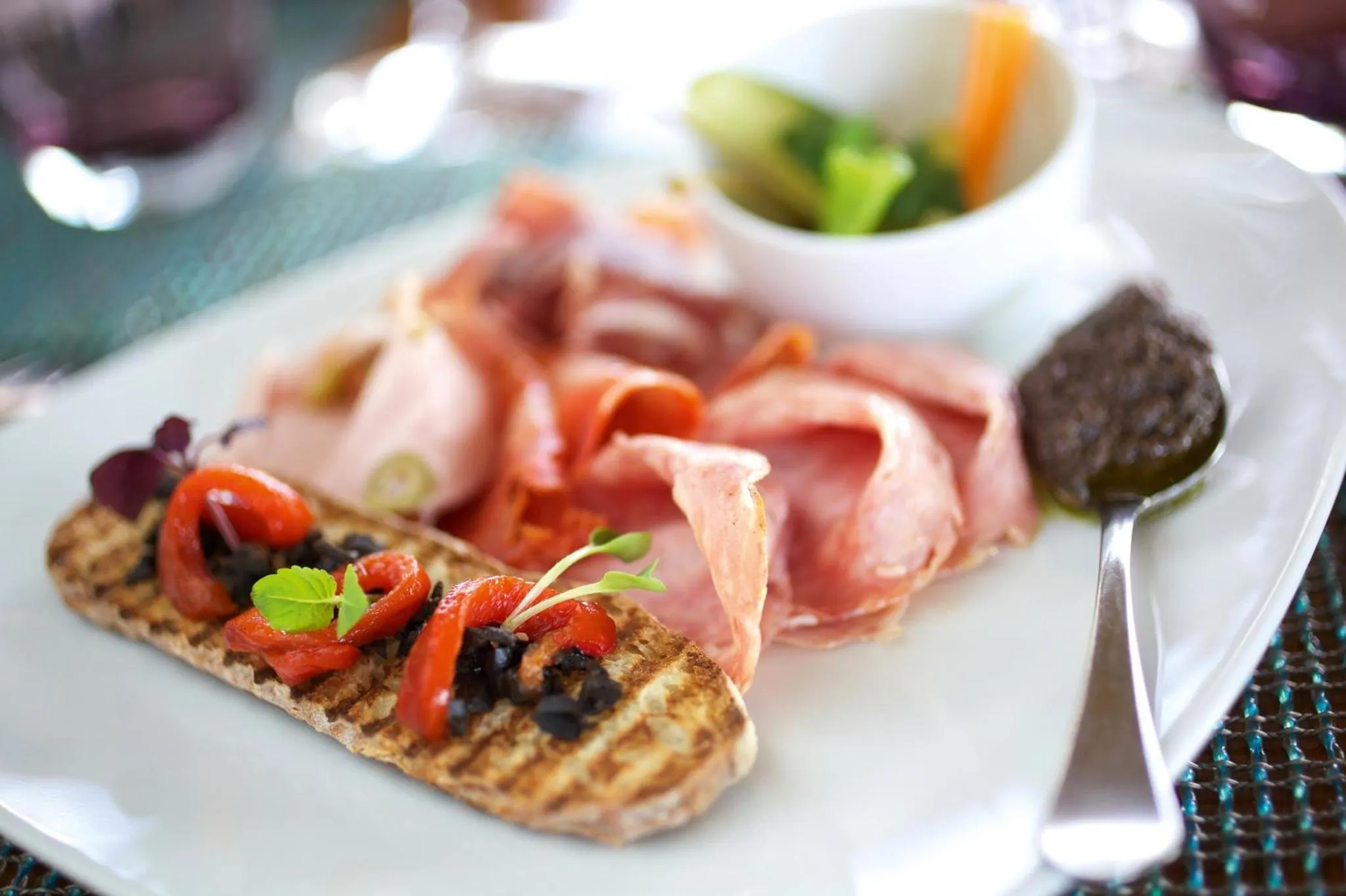 Assiette de charcuterie et de légumes frais présentée sur une table.