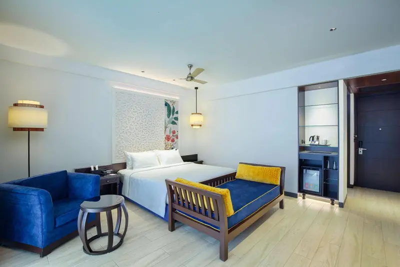 Une chambre lumineuse avec un lit double, un canapé bleu et un espace détente.