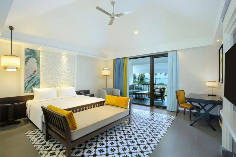 Chambre lumineuse avec un grand lit et un accès à une terrasse.