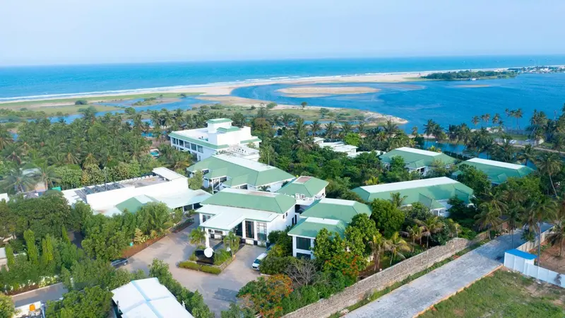 Vue aérienne d'un complexe hôtelier bordant une plage et une lagune.