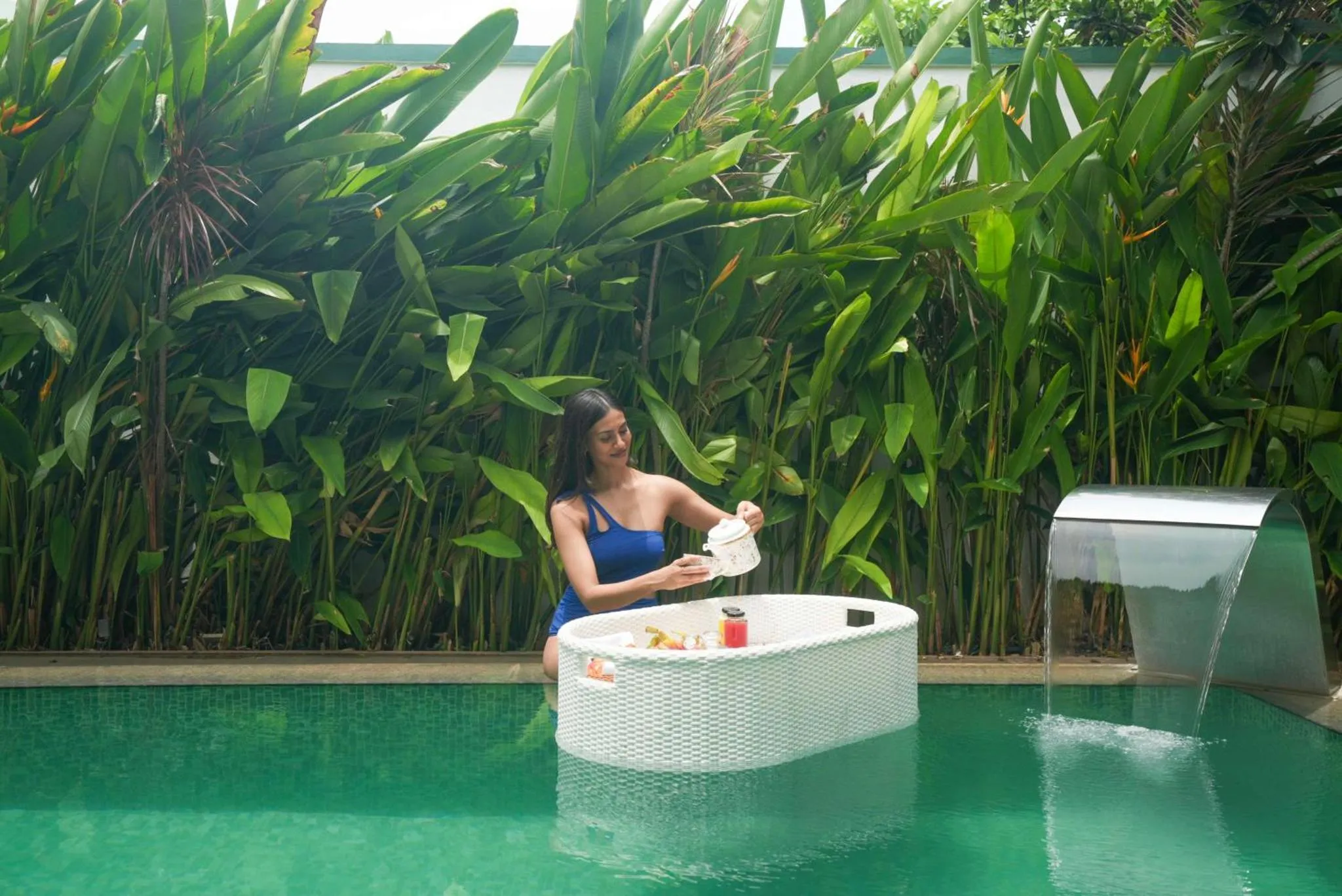 Une femme se détend dans un bain à remous extérieur avec une cascade.