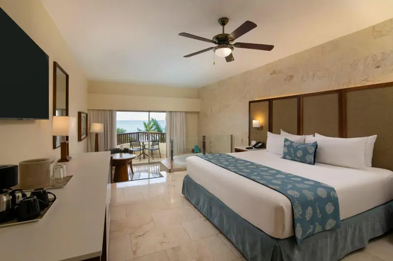 Une chambre lumineuse avec un grand lit et un balcon donnant sur la mer.