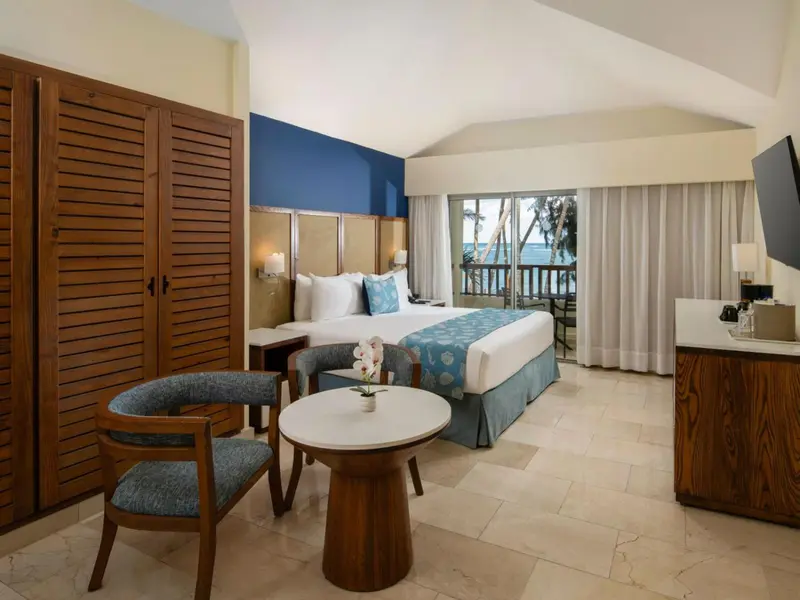 Une chambre lumineuse avec un lit double et un coin salon donnant sur une vue extérieure.