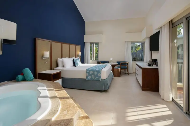 Chambre lumineuse avec un grand lit et un jacuzzi.