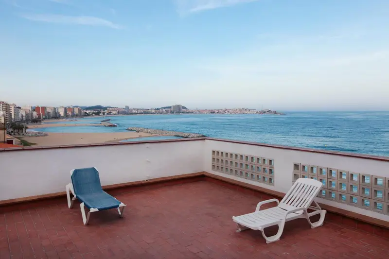 Terrasse avec transats donnant sur la mer et la côte.