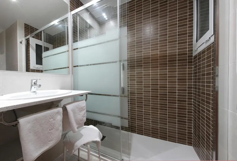 Une salle de bain moderne avec douche vitrée et vasque.