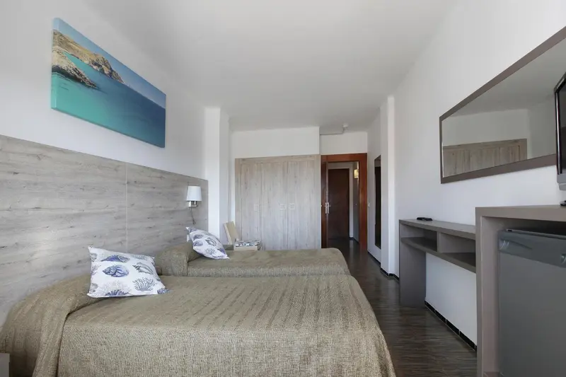 Une chambre lumineuse avec un grand lit et un tableau représentant la mer.