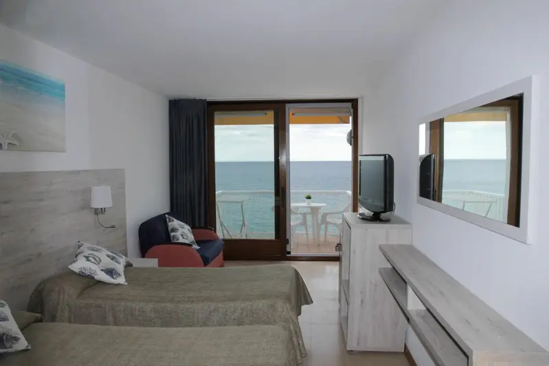 Une chambre lumineuse avec vue sur la mer depuis un balcon.