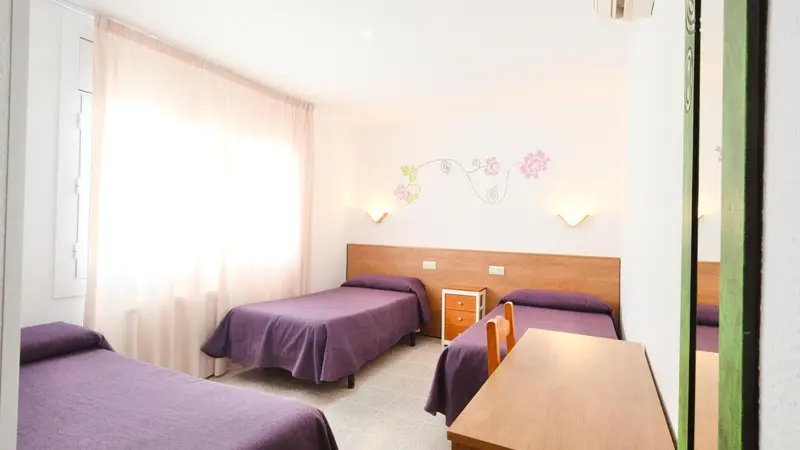 Chambre avec lits simples et décoration florale sur le mur.