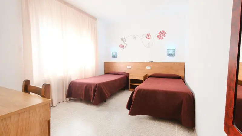 Une chambre avec deux lits simples et une décoration florale au mur.