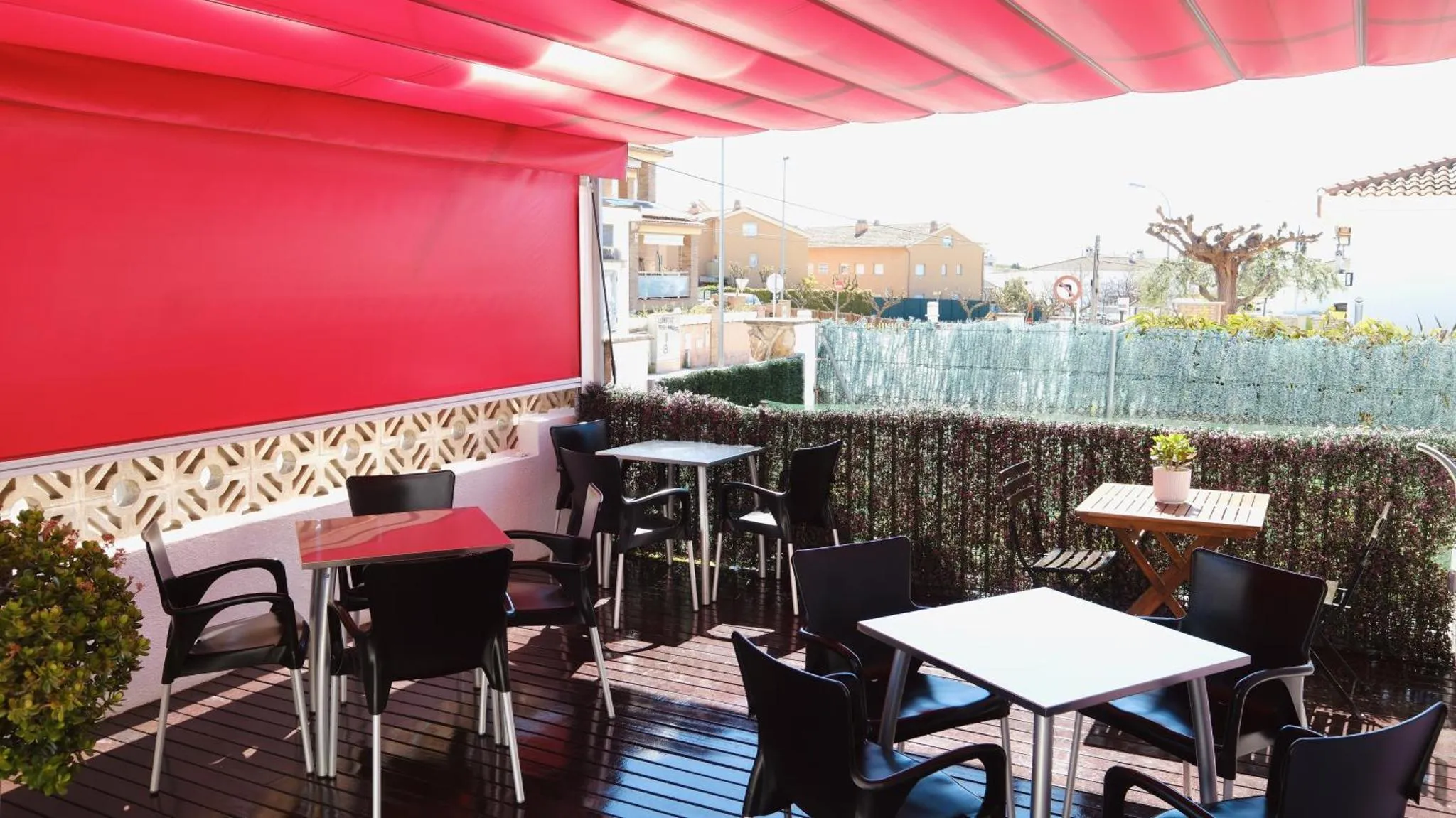 Terrasse ombragée avec tables et chaises en plastique.