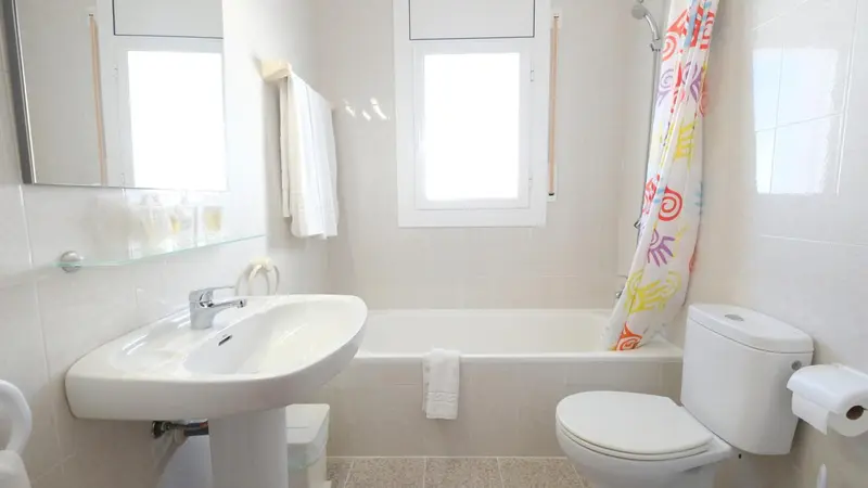 Une salle de bain lumineuse avec baignoire et lavabo.