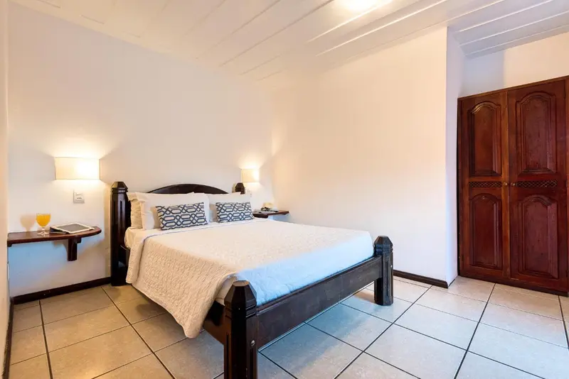 Une chambre lumineuse avec un grand lit et un meuble en bois sombre.