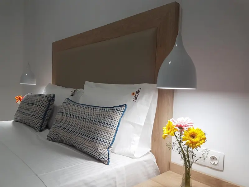 Un lit avec des oreillers et une décoration florale sur une table de chevet.