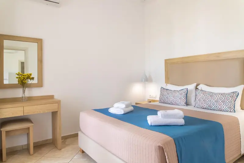 Une chambre lumineuse avec un lit fait et un coin coiffeuse.