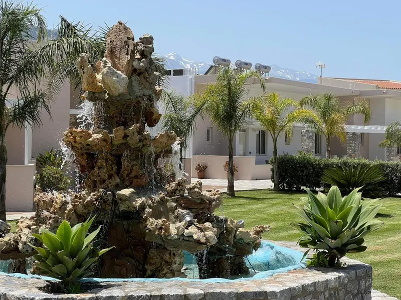 Une fontaine orne un jardin verdoyant devant un bâtiment.