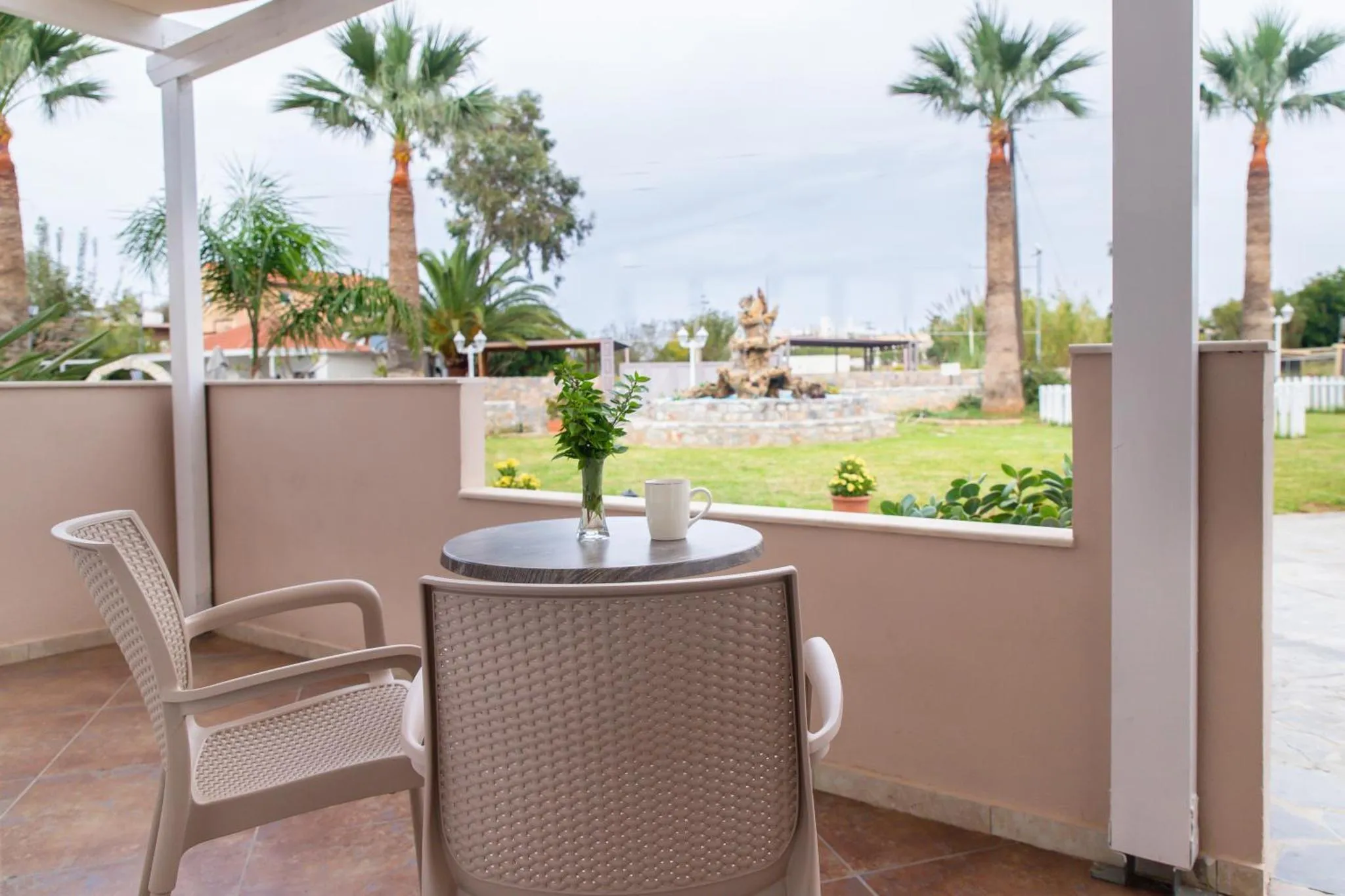 Une table ronde et une chaise en osier sur une terrasse ombragée.