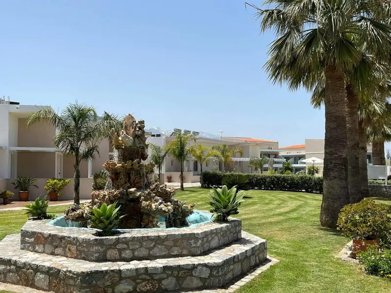 Un jardin verdoyant orné d'une fontaine en pierre et de palmiers.