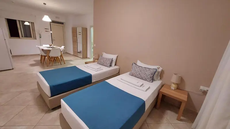 Une chambre lumineuse avec deux lits simples et une table à manger.