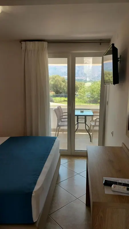 Une chambre lumineuse s'ouvre sur une terrasse avec vue sur le paysage.