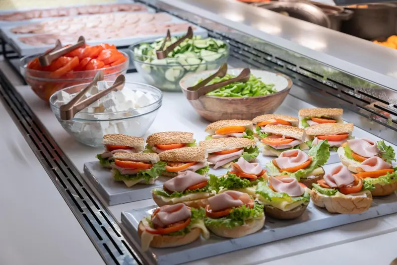 Présentation de sandwichs, salades et crudités sur un buffet.
