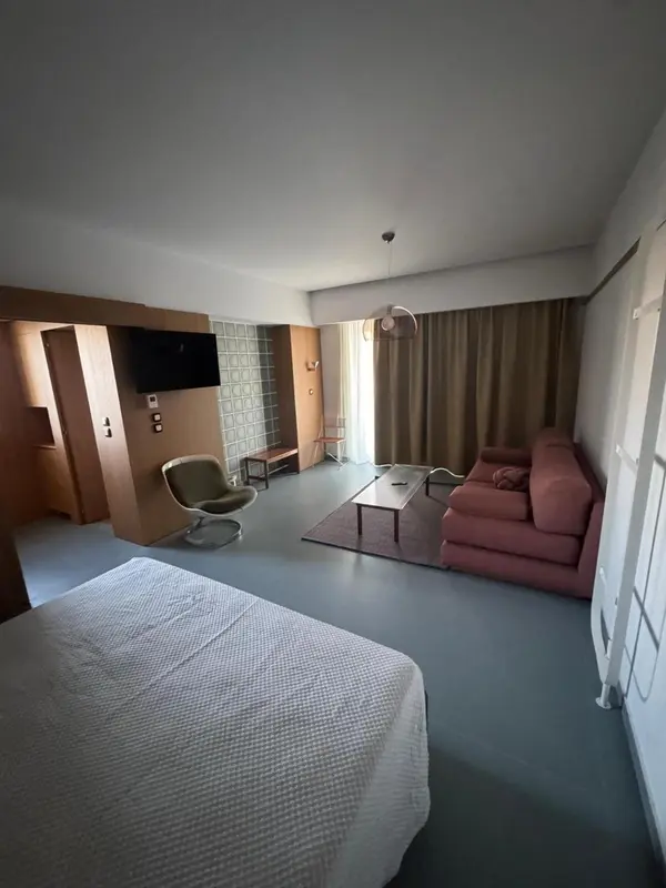 Une chambre lumineuse avec un coin salon et un lit.