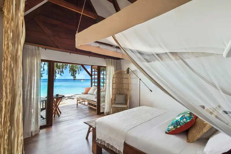Une chambre lumineuse avec un lit à baldaquin donnant sur une plage.