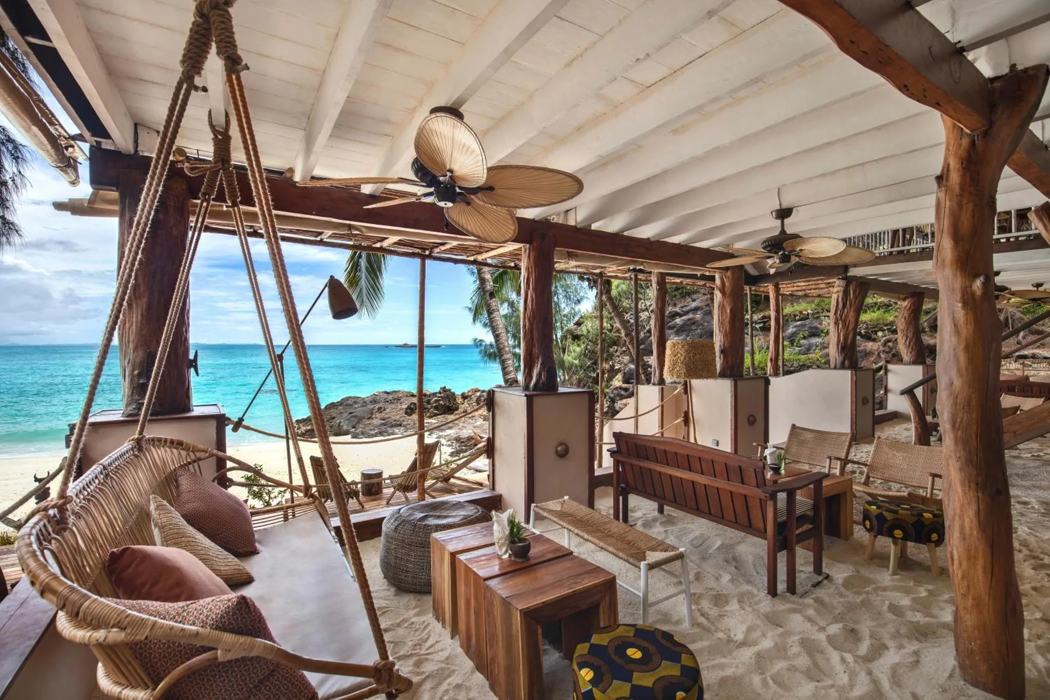 Espace de détente en bois avec vue sur la mer turquoise et le sable blanc.