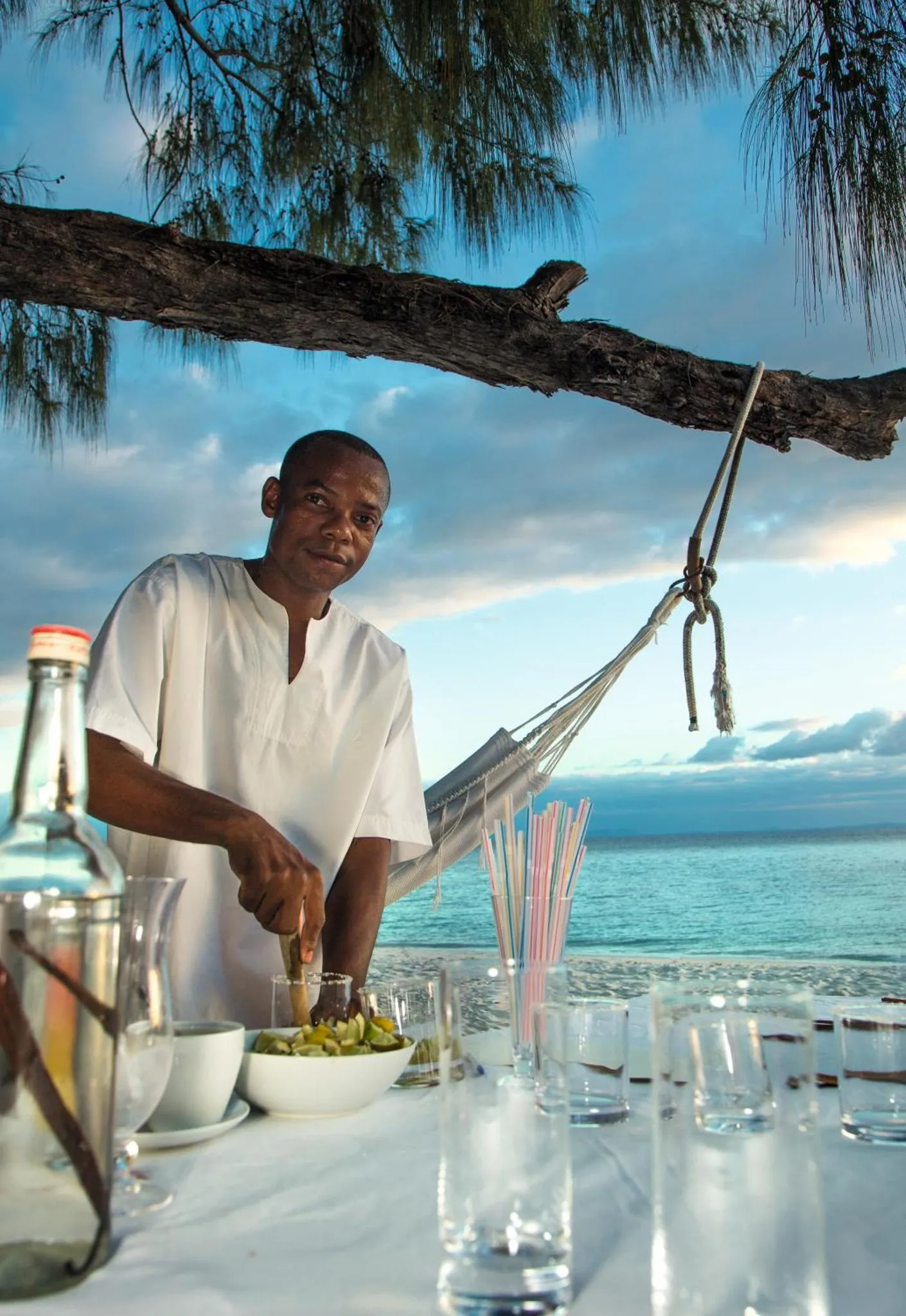Un homme prépare des boissons sur une table en bord de mer.