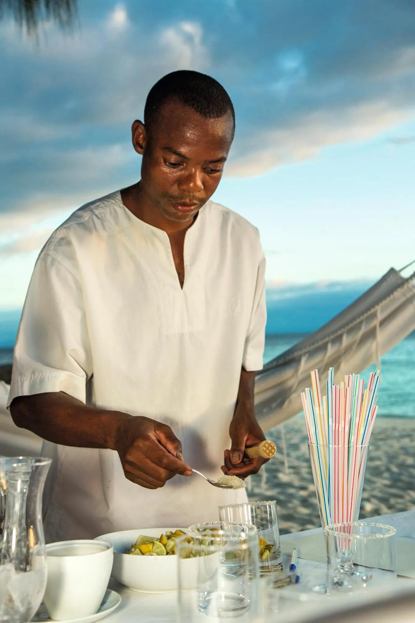 Un homme prépare des boissons sur une table en bord de mer.