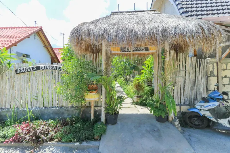 Entree d'un bungalow avec toiture de chaume et vegetation tropicale.